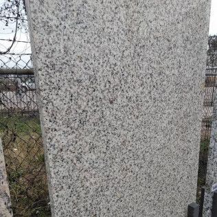 Close-up of a speckled gray stone surface beside a chain-link fence outdoors