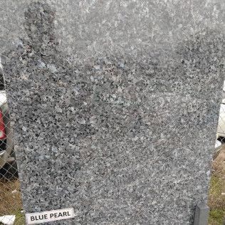 Gray speckled granite slab labeled “Blue Pearl” at a stone yard