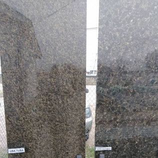 Two polished dark granite slabs with a narrow gap, showing a bright outdoor view between them.