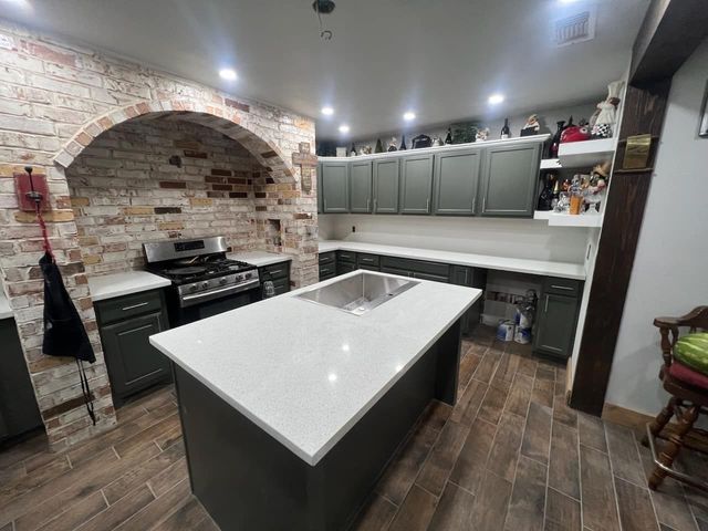 Modern kitchen with brick arch, gray cabinets, and a white island countertop