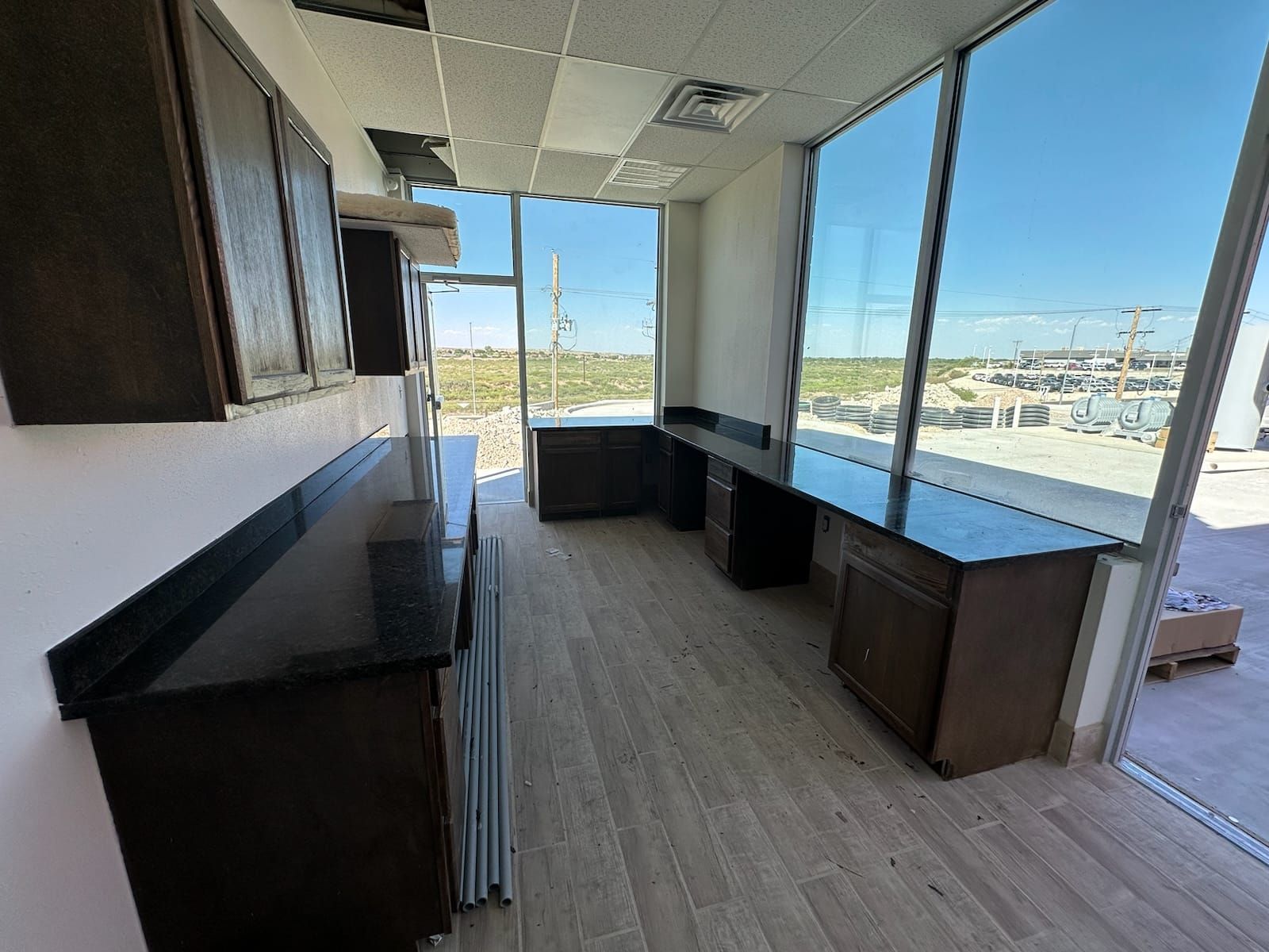Empty office with dark wood desks, wood floors, and large windows overlooking a waterfront.