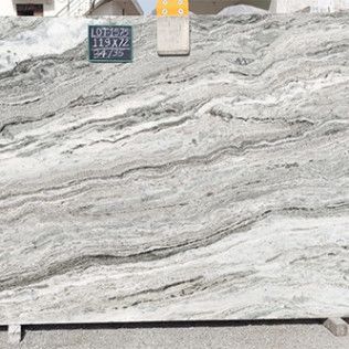 Large white and gray veined marble slab displayed on a pallet in a stone yard