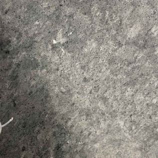 Close-up of a gray, textured stone surface with a dark shadow along the left edge