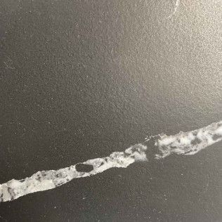 Close-up of a gray surface with a jagged white crack running diagonally across it
