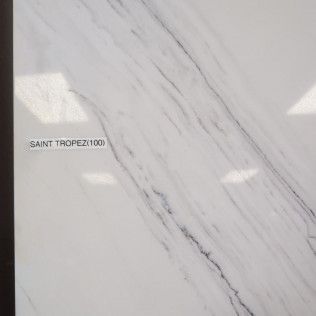 White marble tile with subtle gray veining labeled “SAINT TROPEZ/1000”