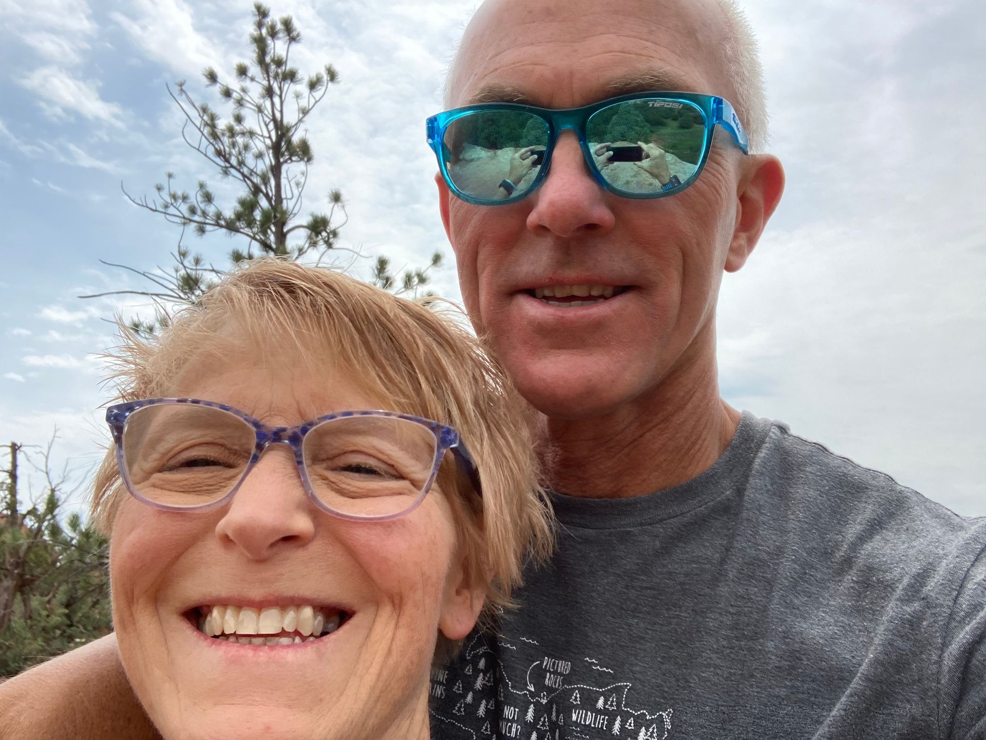 A man and a woman wearing sunglasses are smiling for the camera.