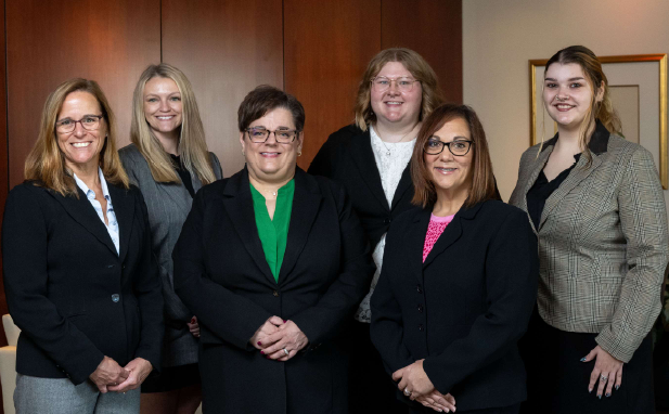 Group of women in suits posing in an office setting.