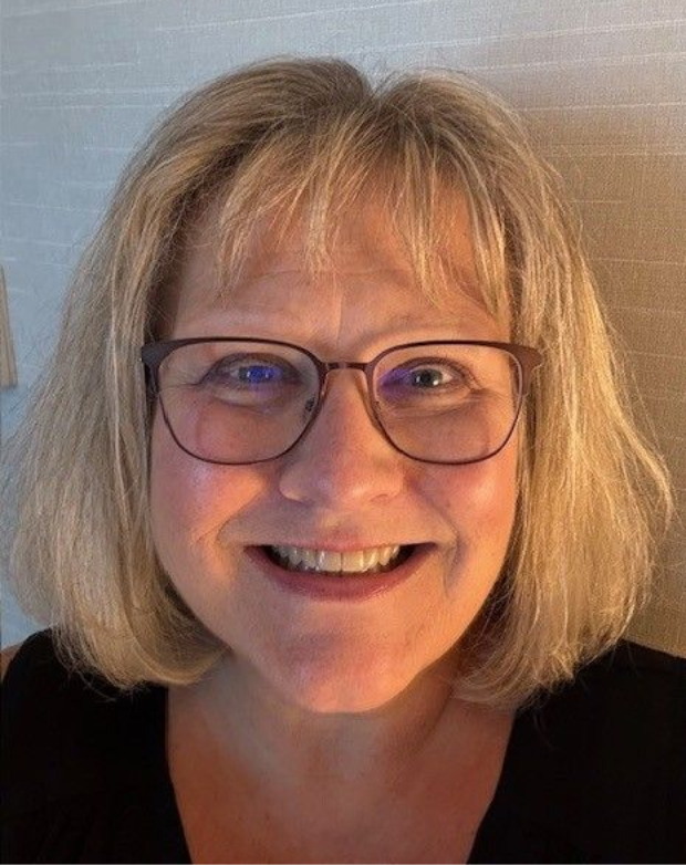 Woman with blonde hair and glasses smiles at the camera.