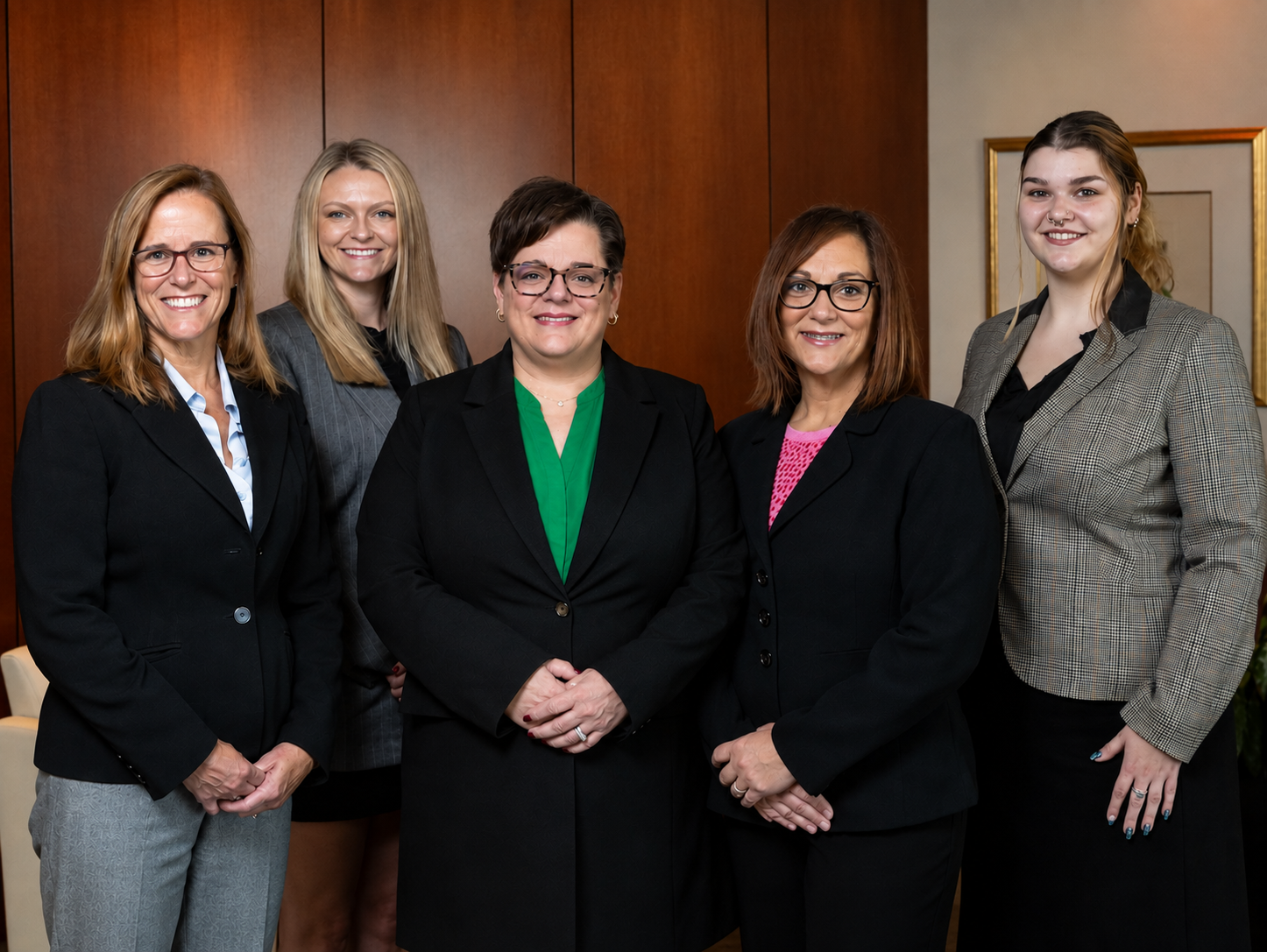 Group of women in suits posing in an office setting.