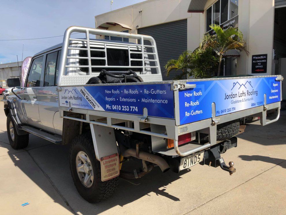 A Silver Truck With a Blue Bed is Parked in Front of a Building — Signtek Gladstone in Bundaberg, QLD