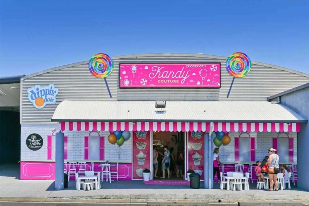 A candy store with tables and chairs in front of it.