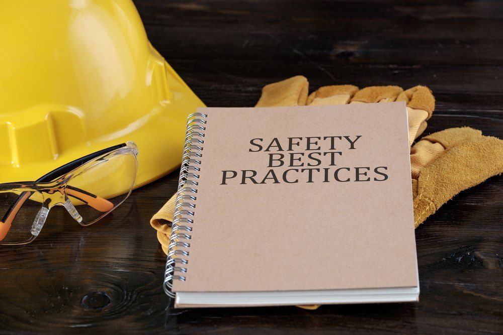 A Book Titled Safety Best Practices Sits Next to a Hard Hat and Gloves — Signtek Gladstone in Gladstone Central, QLD