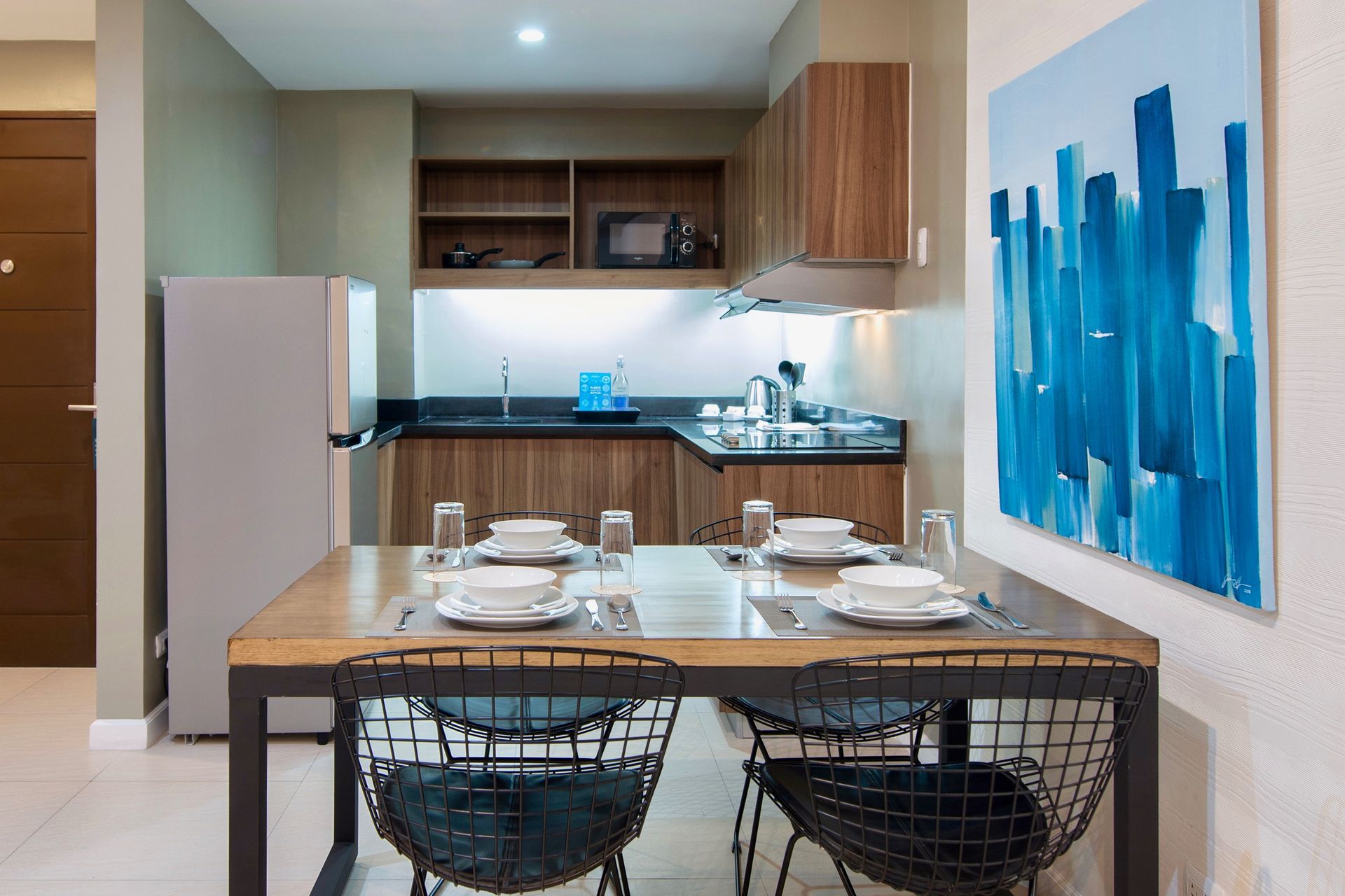 Dining table set for four beside a kitchenette with fridge and microwave in a serviced apartment at The Sphere Makati