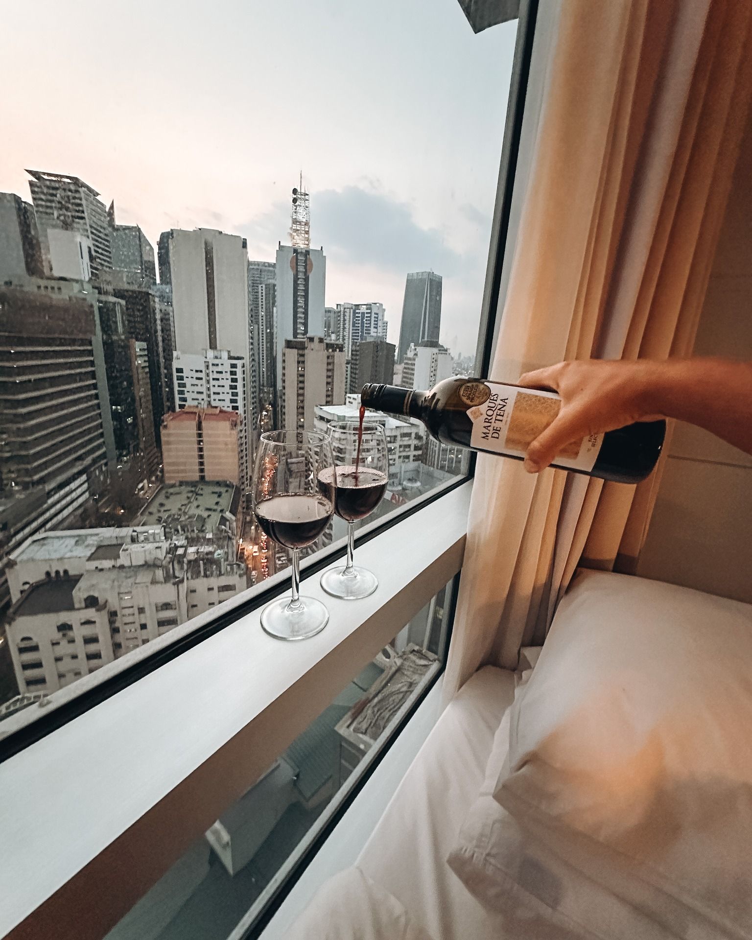 Pouring Marqués de Tena red wine with Makati skyline view