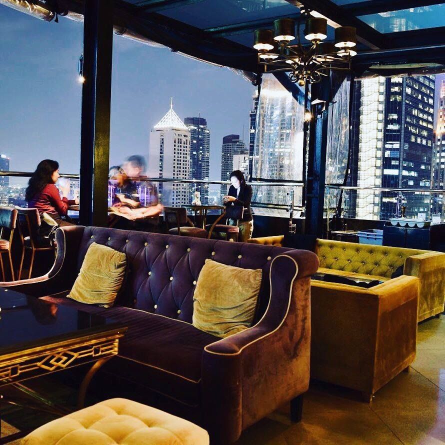 Rooftop lounge with velvet sofas and Makati city skyline at night