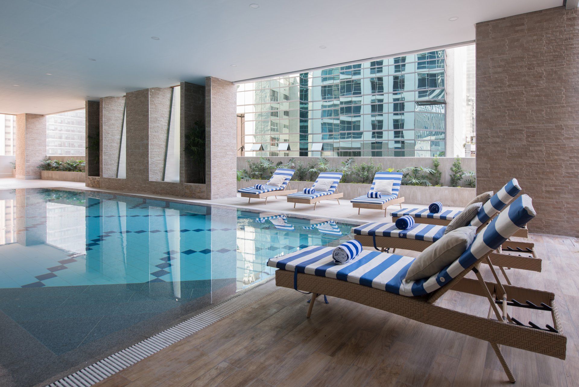 Luxury indoor pool with blue striped loungers at The Sphere Makati