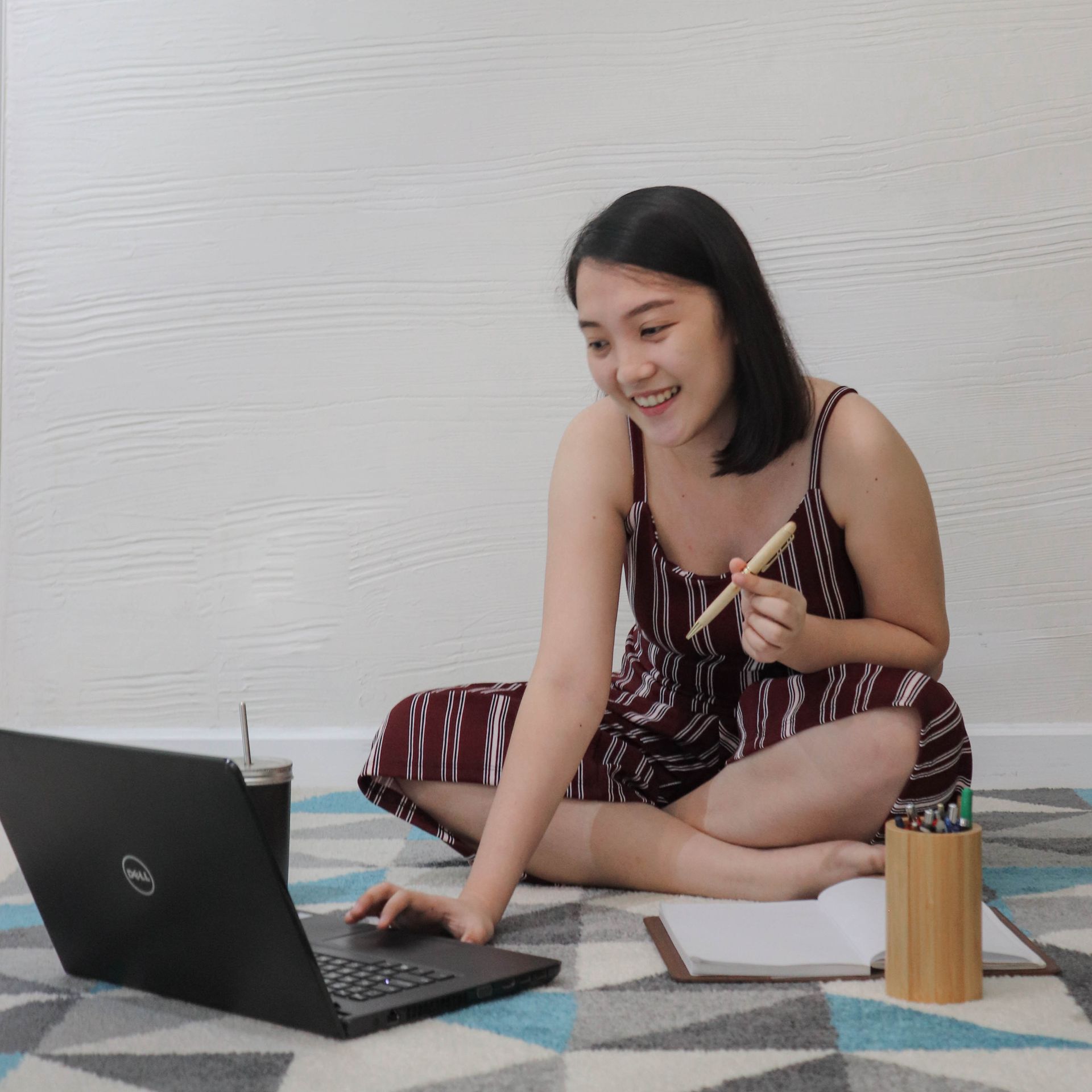 Smiling guest working on a laptop while seated on the geometric rug of a serviced apartment at The Sphere Makati