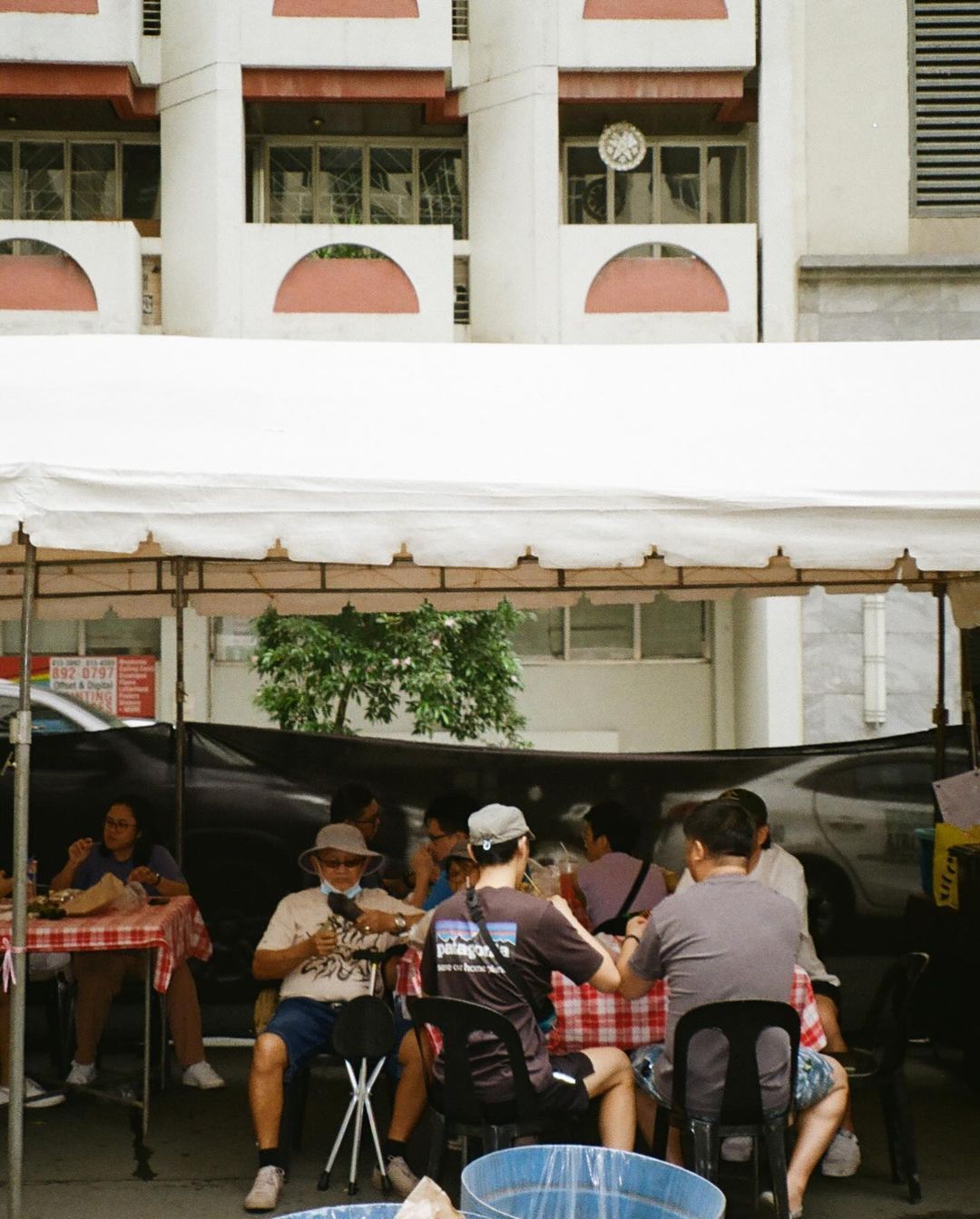 A group of people are sitting at tables under a tent in Salced