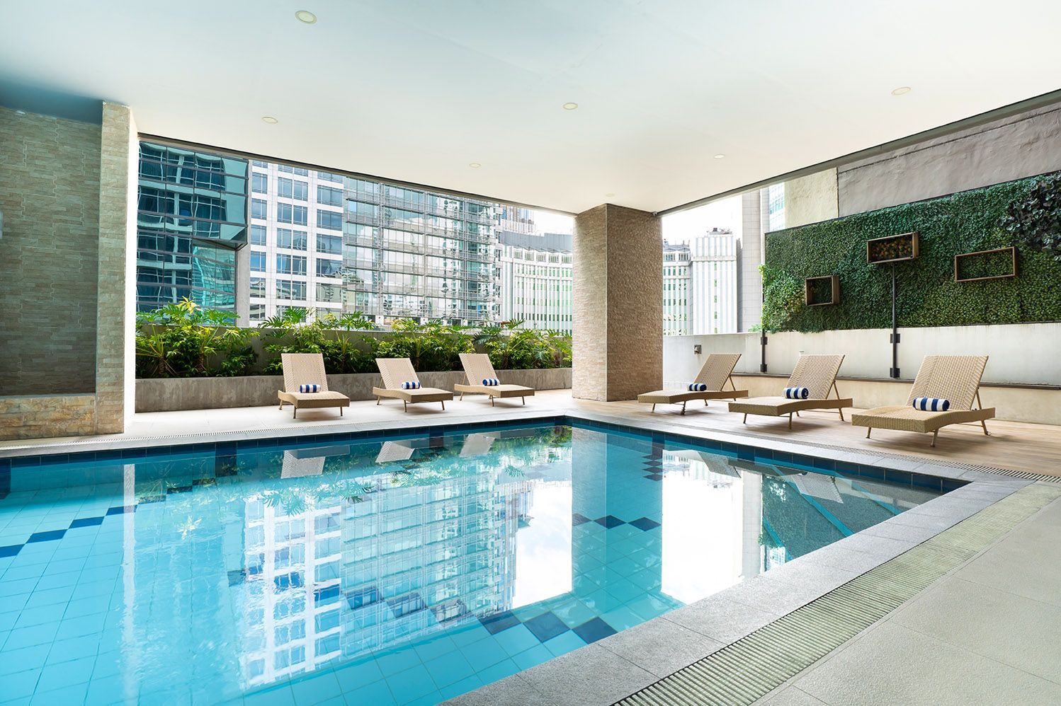 Indoor swimming pool with lounge chairs and city views.