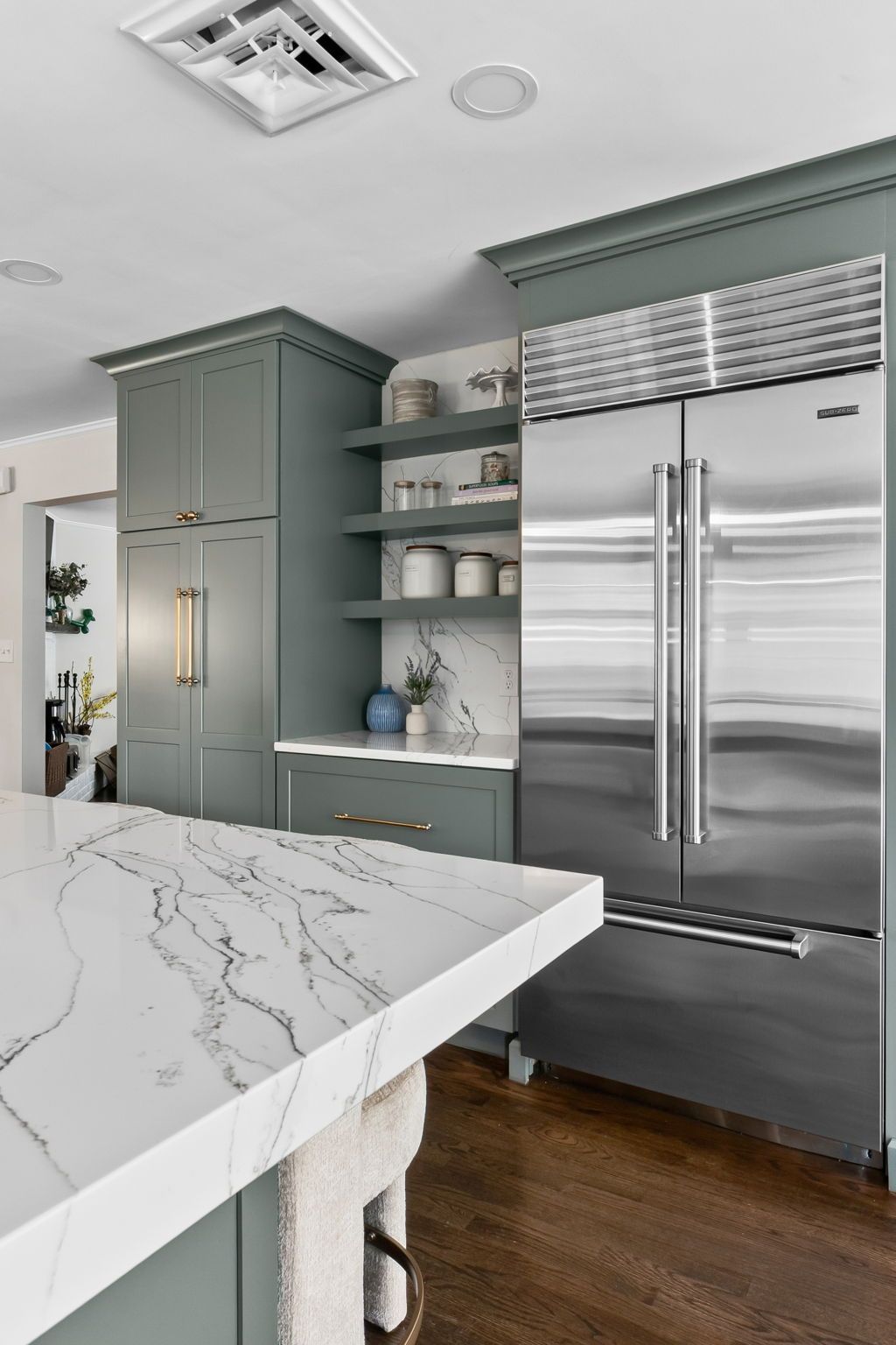Modern kitchen with stainless steel refrigerator, gray cabinets, and a white marble island