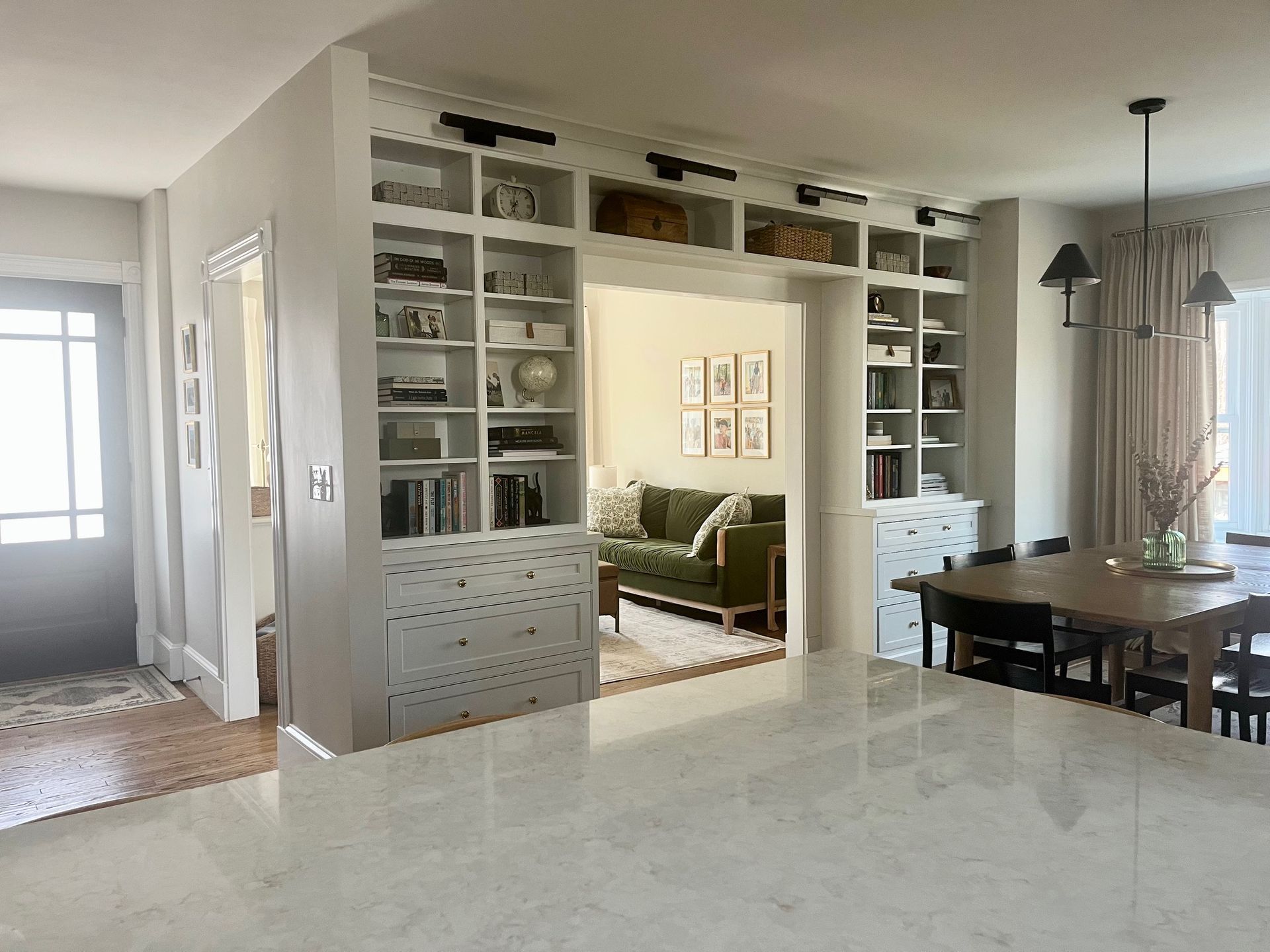 A living room with a couch , table , chairs and shelves.