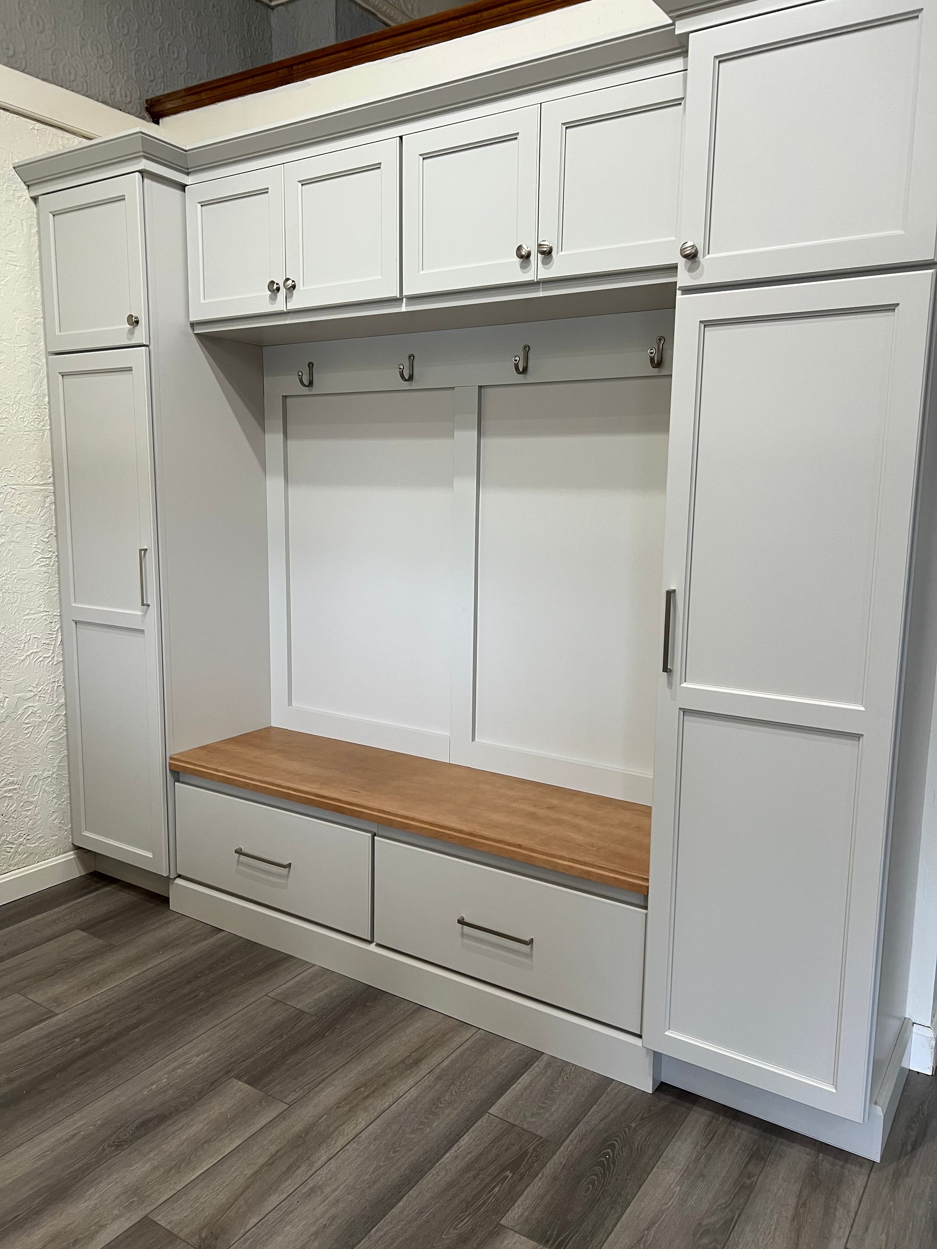 A room with white cabinets and a wooden bench.