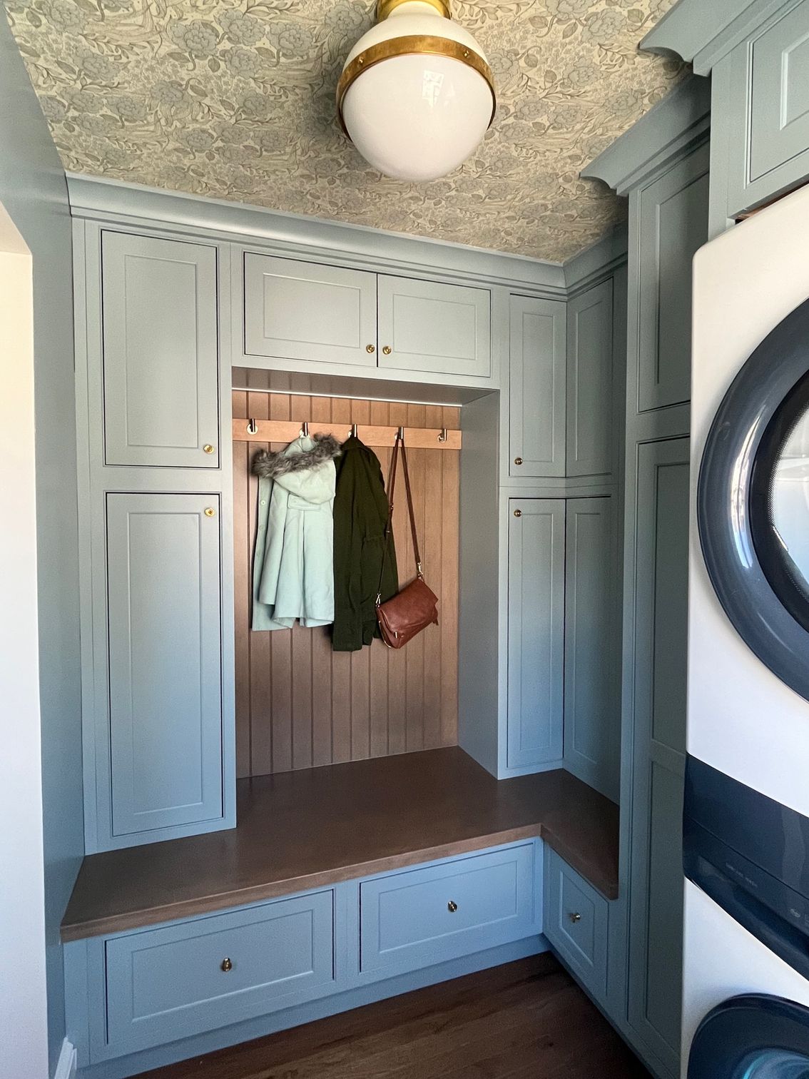 A laundry room with a bench and a washer and dryer.