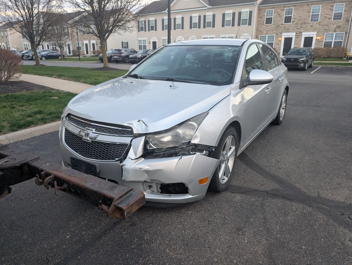 Silver sedan with front-end damage after hitting a parking barrier in a residential lot