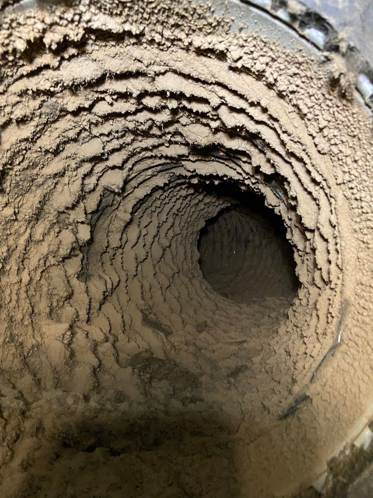 A close up of a dirty duct with a hole in the middle.