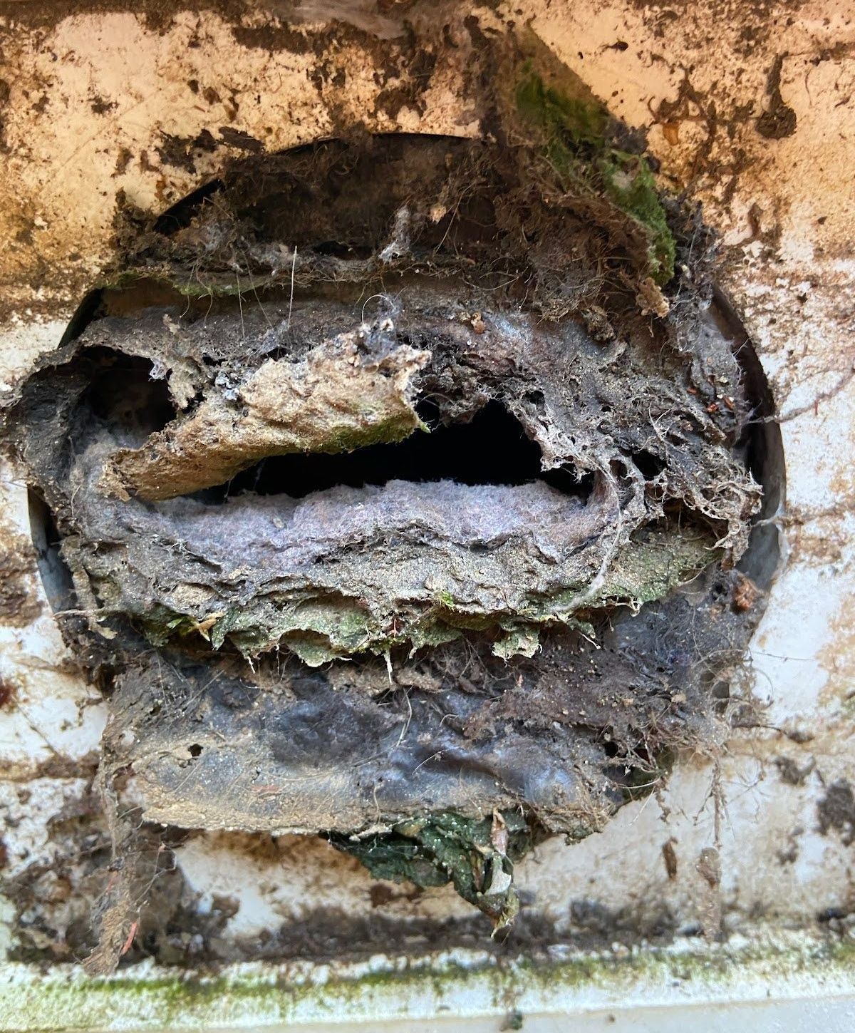 A close up of a dirty duct with a hole in the middle.