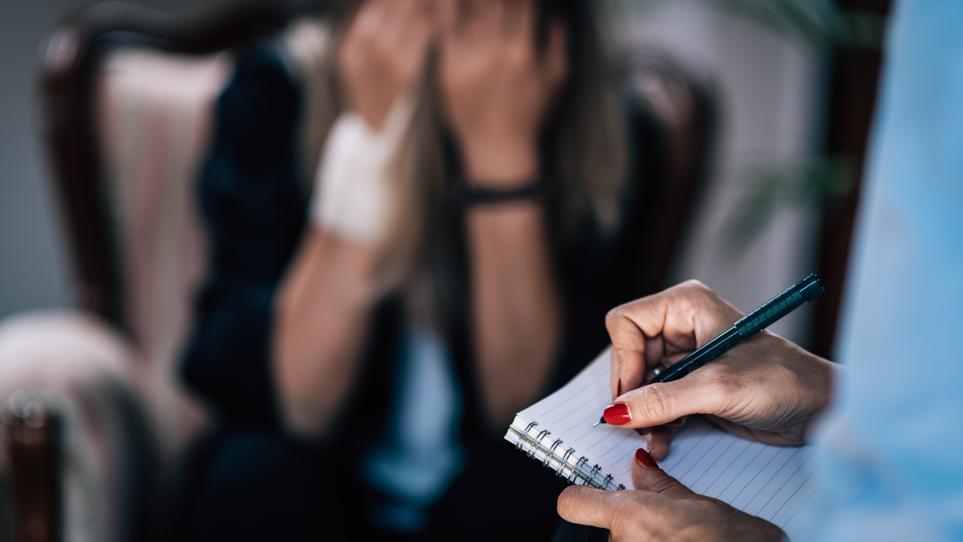 Hand writing notes on a notepad during a blurred interview or conversation