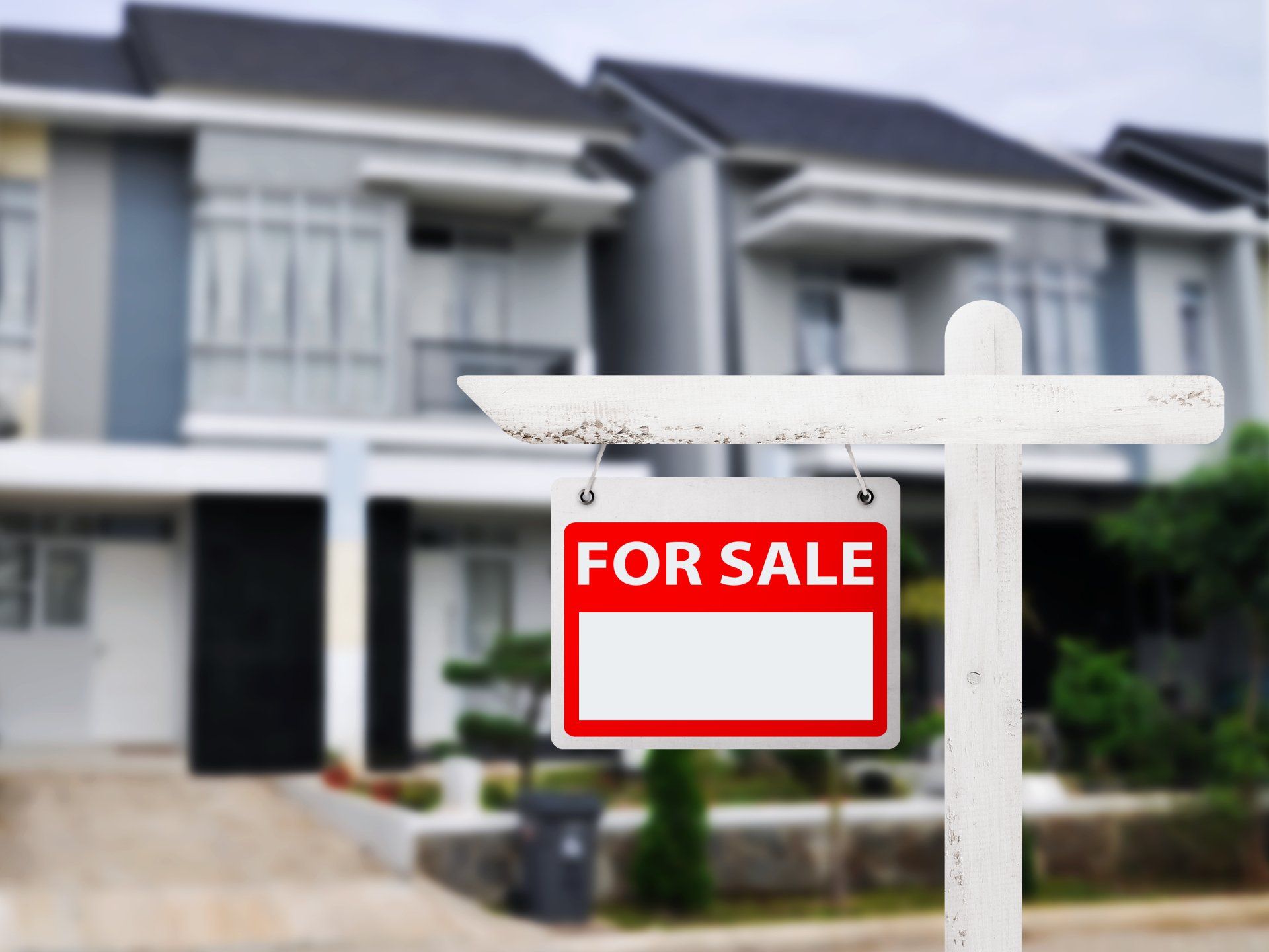 townhome with for sale sign in front of it