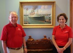 jay and mary silberman A man and a woman are standing in front of a painting of a ship.