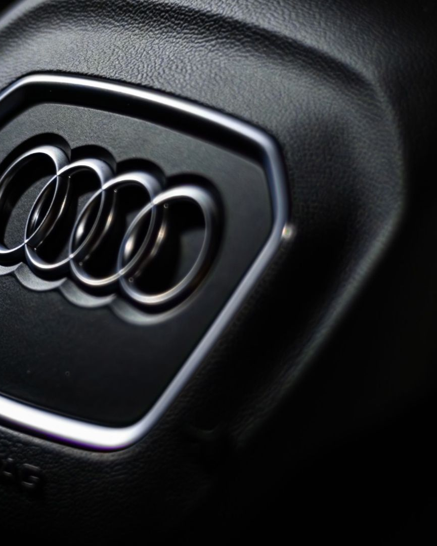 Close-up of the Audi logo on a glossy black car grille