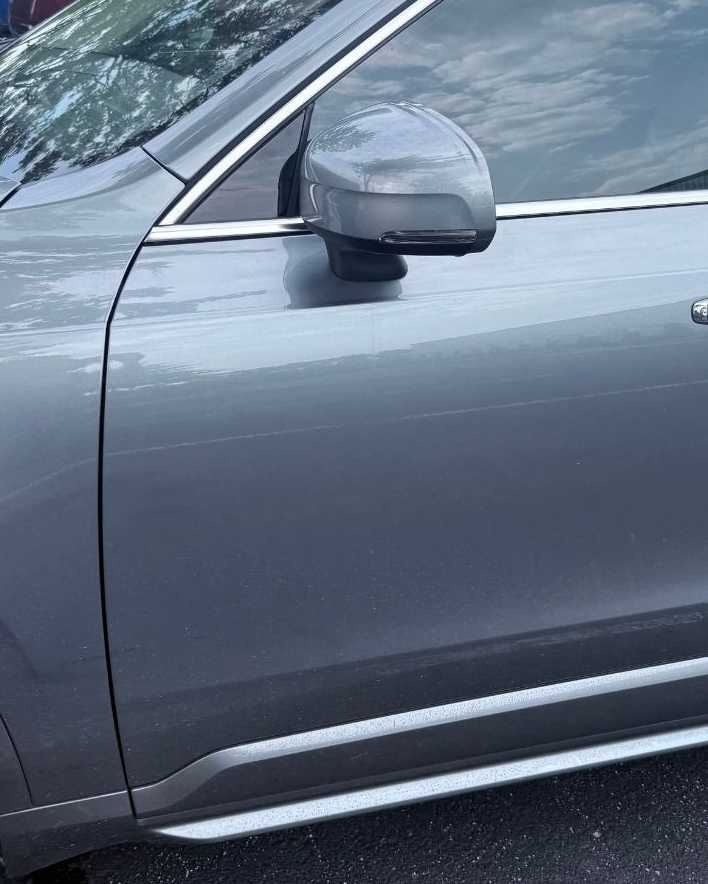 Gray car side view with a side mirror and door panel detailing
