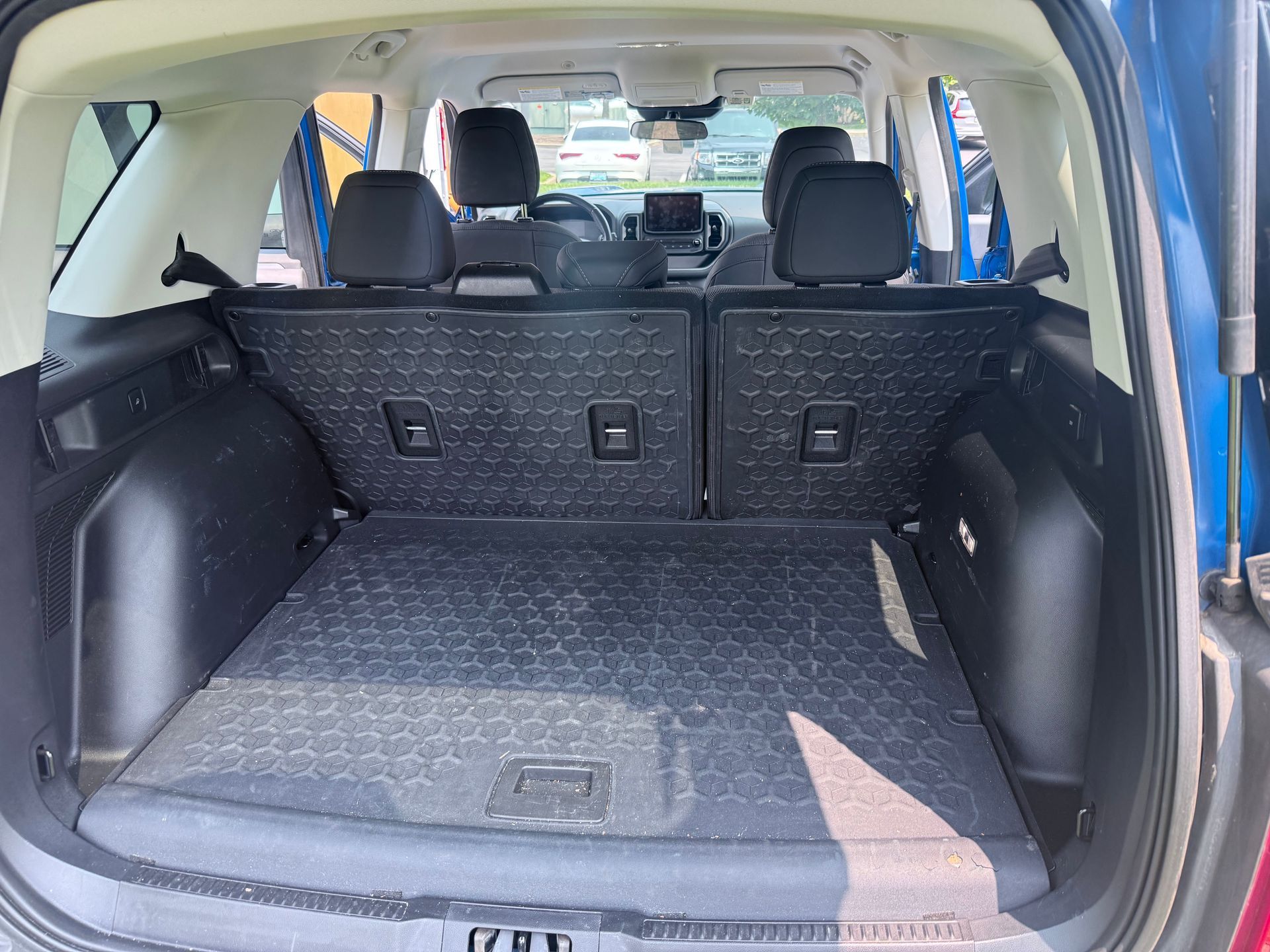 Open SUV cargo area with folded rear seats and gray patterned trunk mat