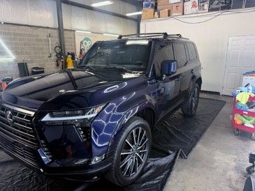 Dark blue SUV inside an auto shop garage, parked on a lift mat.