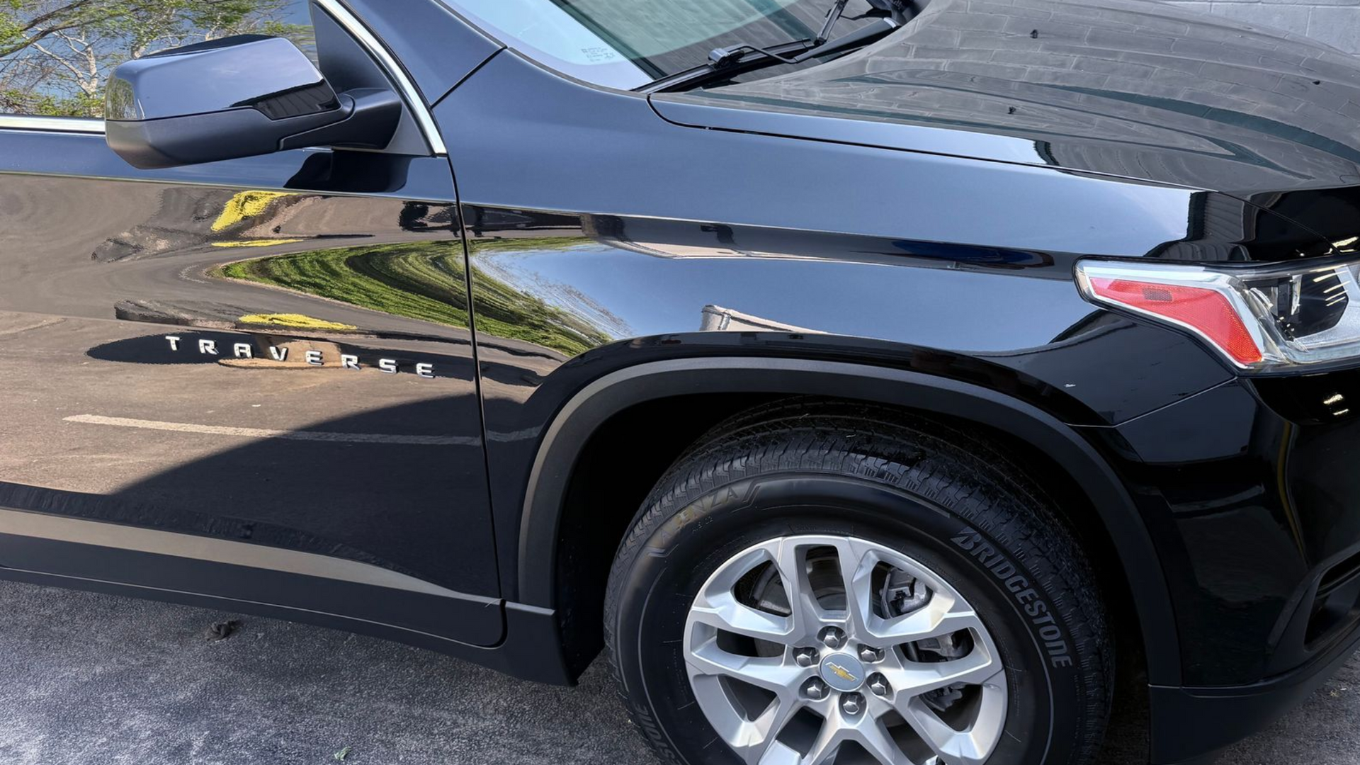 Black SUV parked on a street, side view with front wheel and mirror visible.