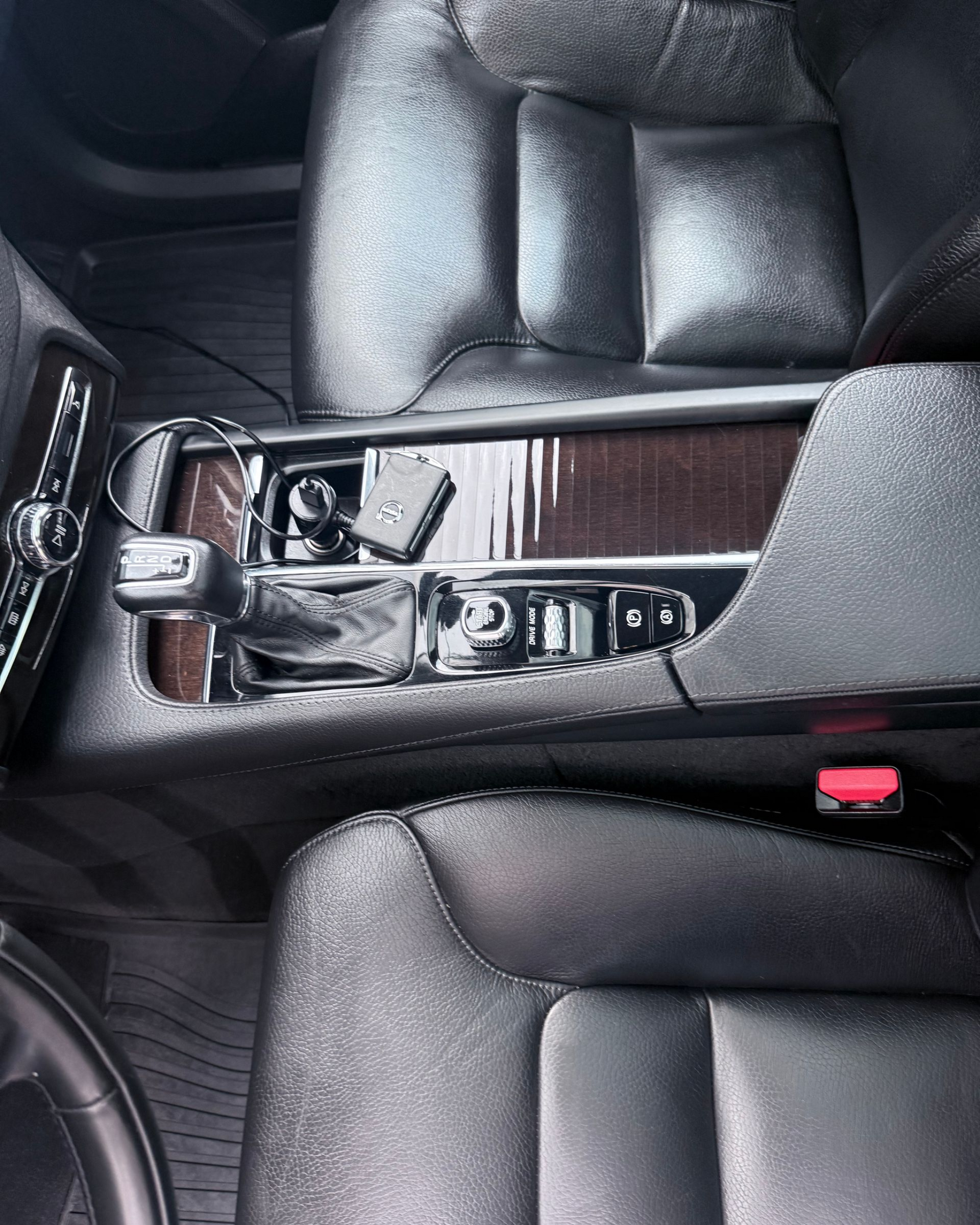 Car interior with black leather seats and center console featuring cup holders and wood trim