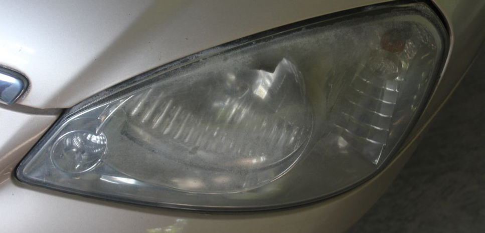 Close-up of a car’s cloudy headlight lens on a silver vehicle