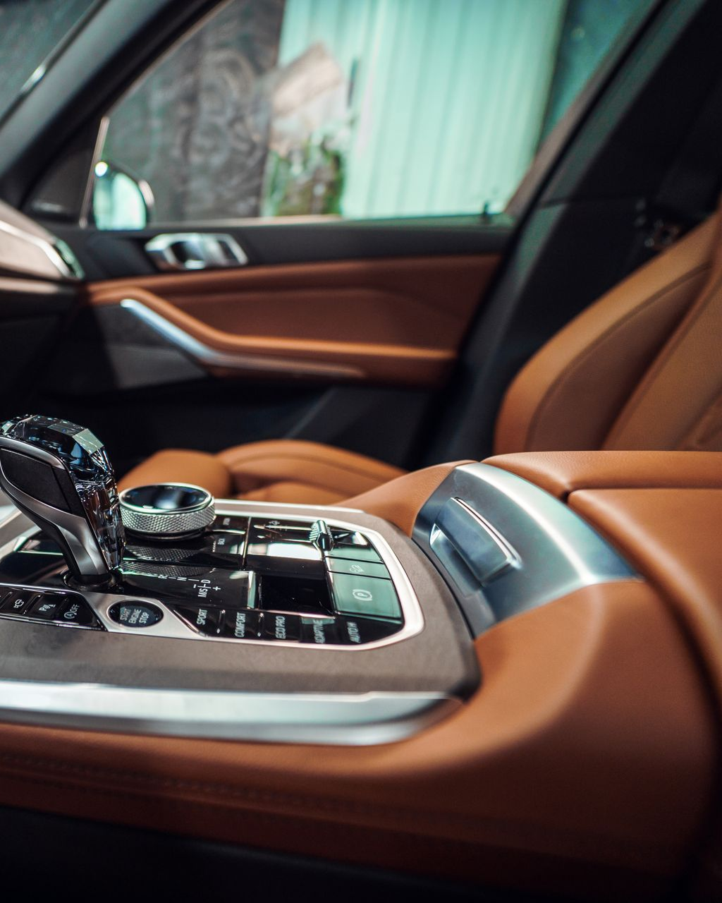 Luxury car interior with tan leather seats and a center console with gear selector and controls
