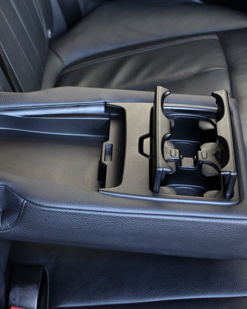 Car cup holder and storage tray in a car center console, black interior