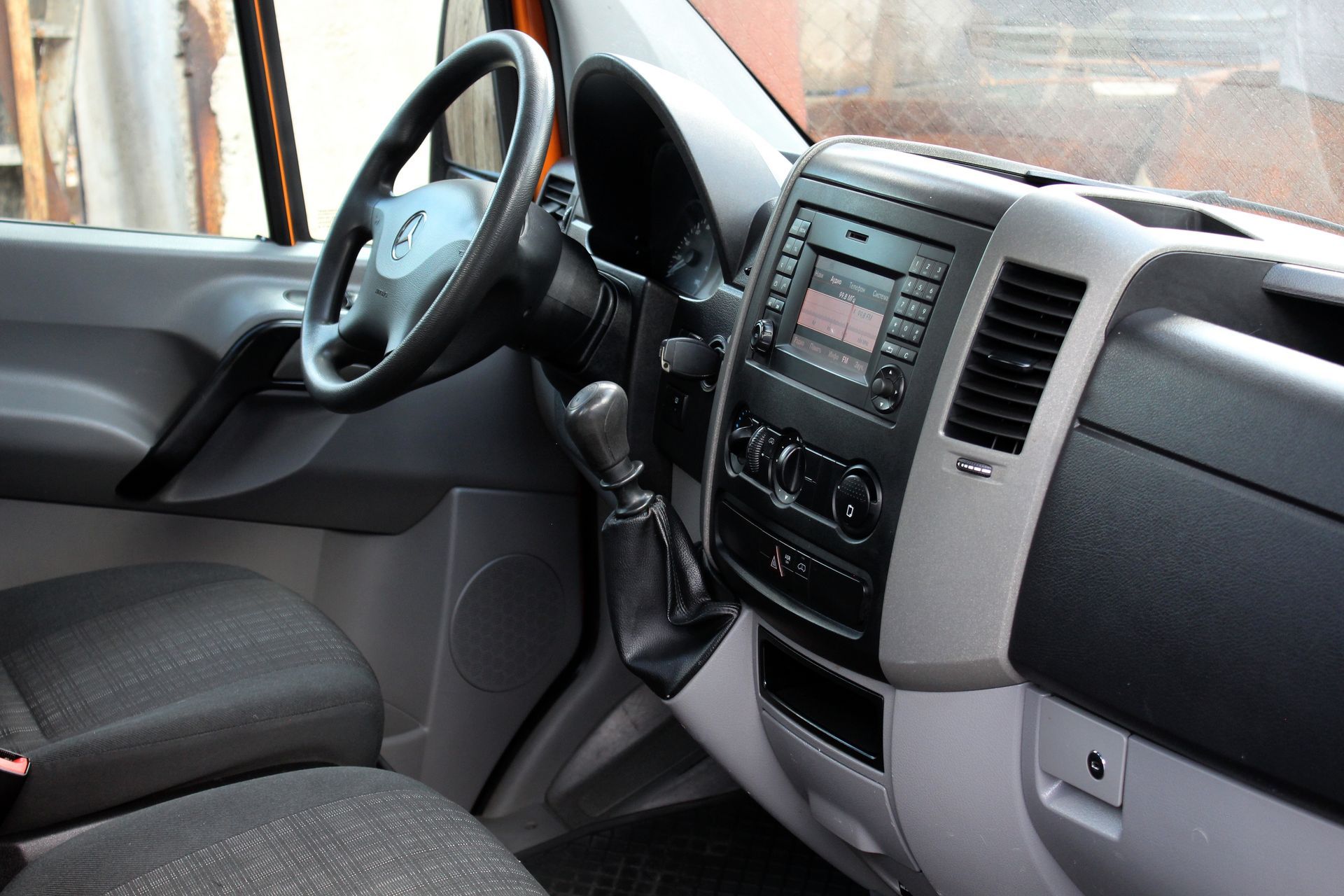 Car interior with dashboard, steering wheel, and front seats in gray and black tones