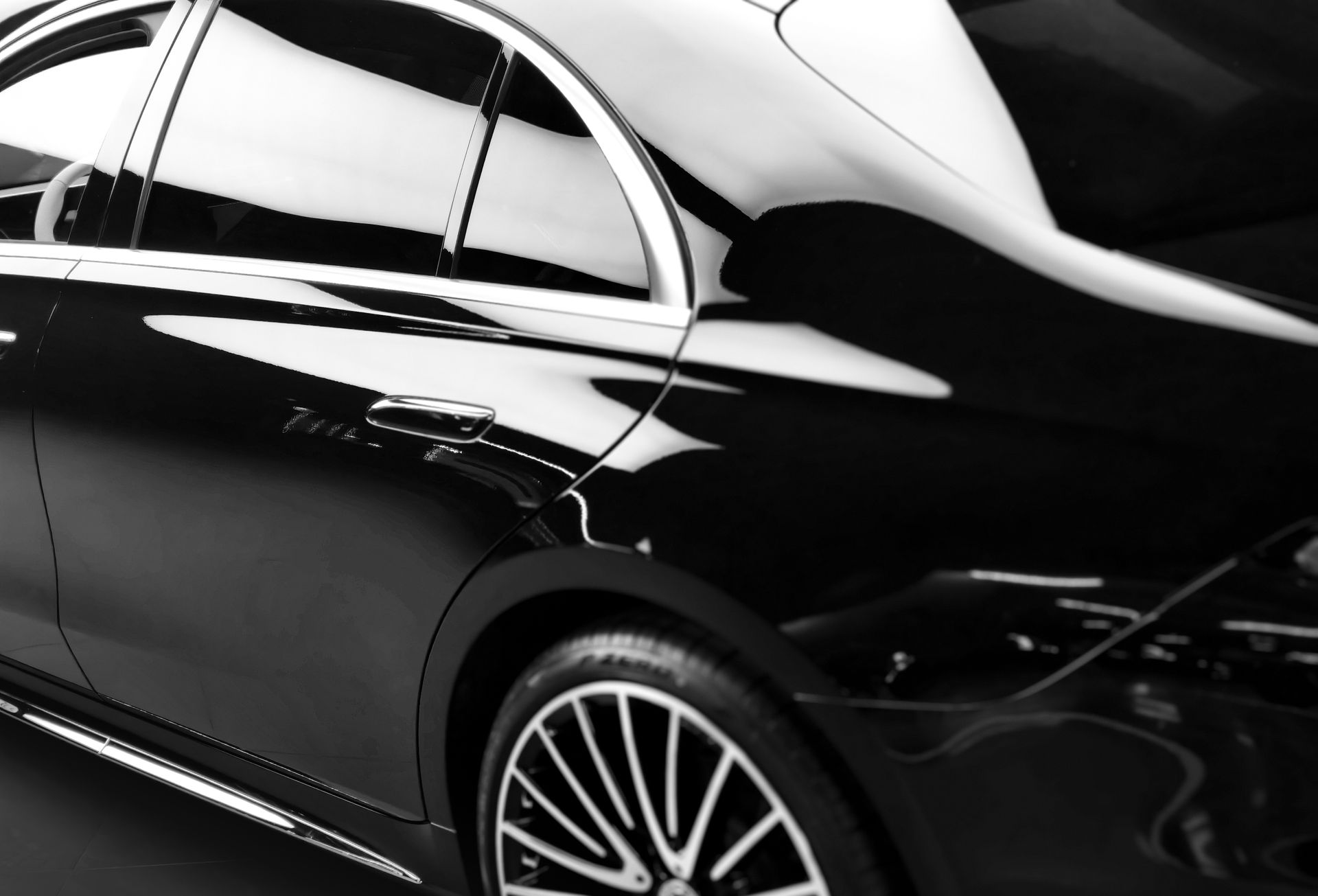 Glossy black luxury sedan side view with chrome trim and alloy wheel