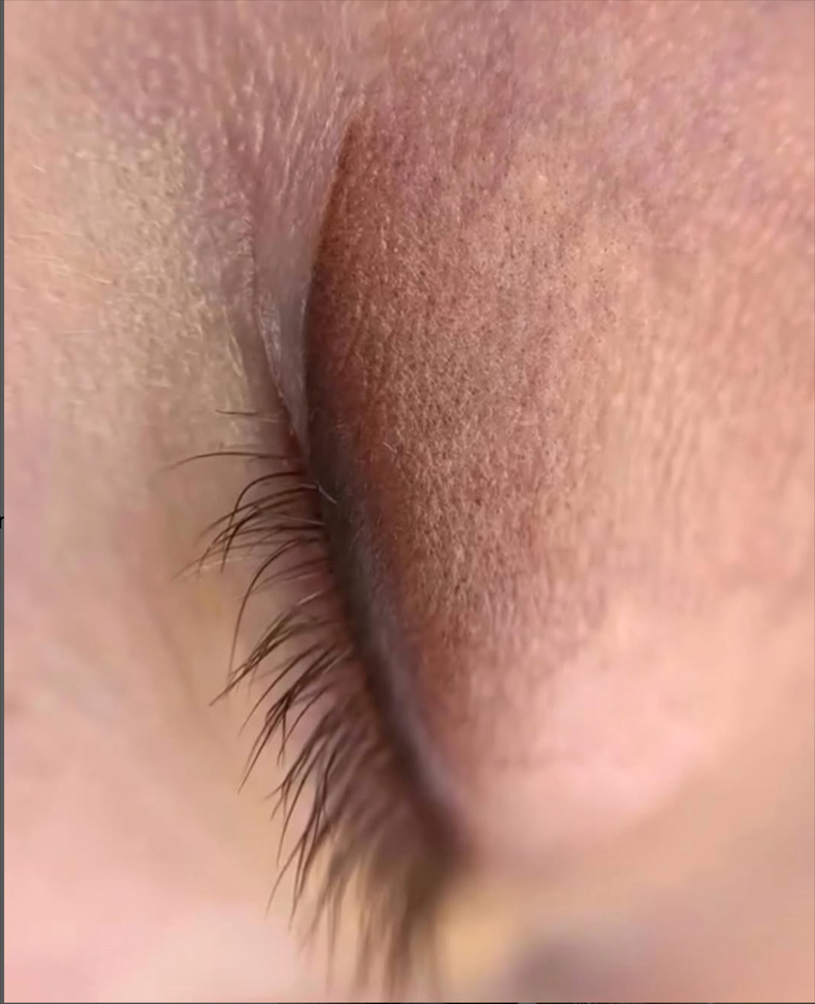 Geschlossenes Augenlid mit dunklen Wimpern. Die Haut ist hell und schattiert.