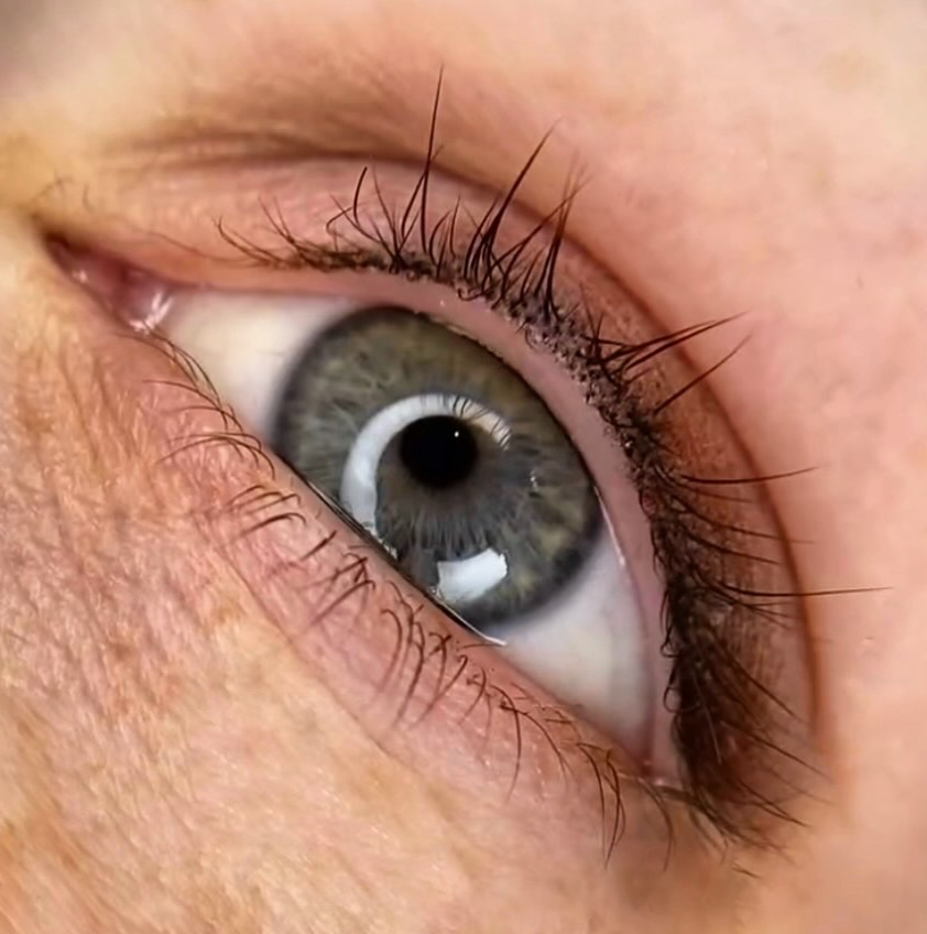 Nahaufnahme eines Auges mit dezentem Lidstrich, grüner Iris und dunklen Wimpern.