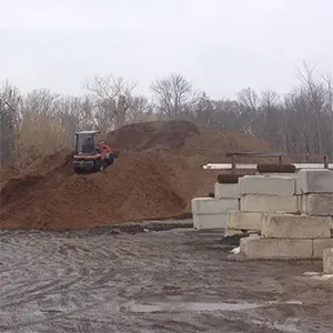 Bulldozer pushing dirt on a muddy construction site beside stacked concrete blocks