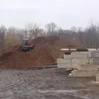 Bulldozer pushing dirt on a muddy construction site beside stacked concrete blocks