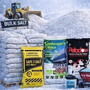 Bulk salt piles and ice melt bags stacked outdoors, with a loader in the snow behind them