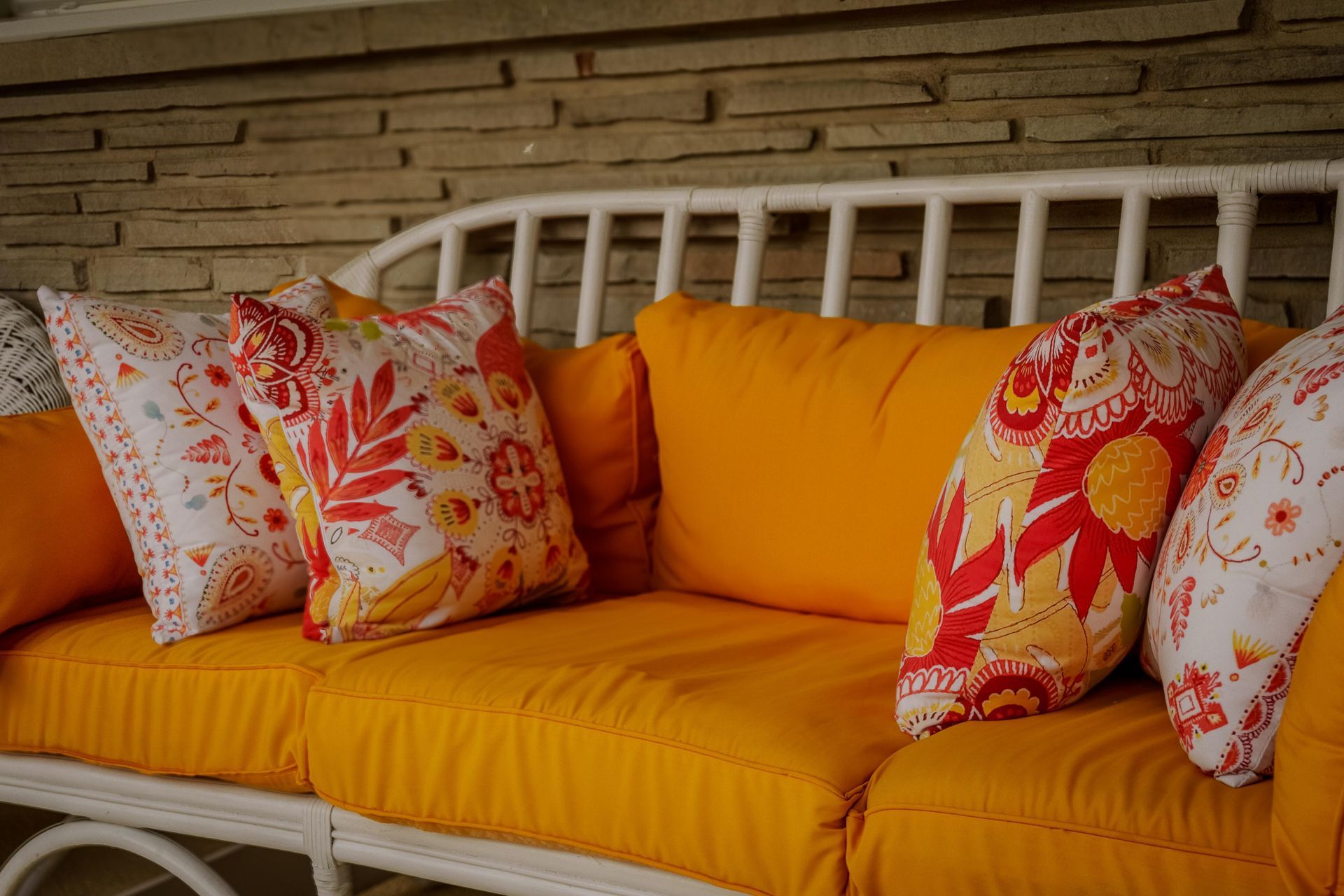 Orange couch with floral pillows and a white wooden backrest indoors
